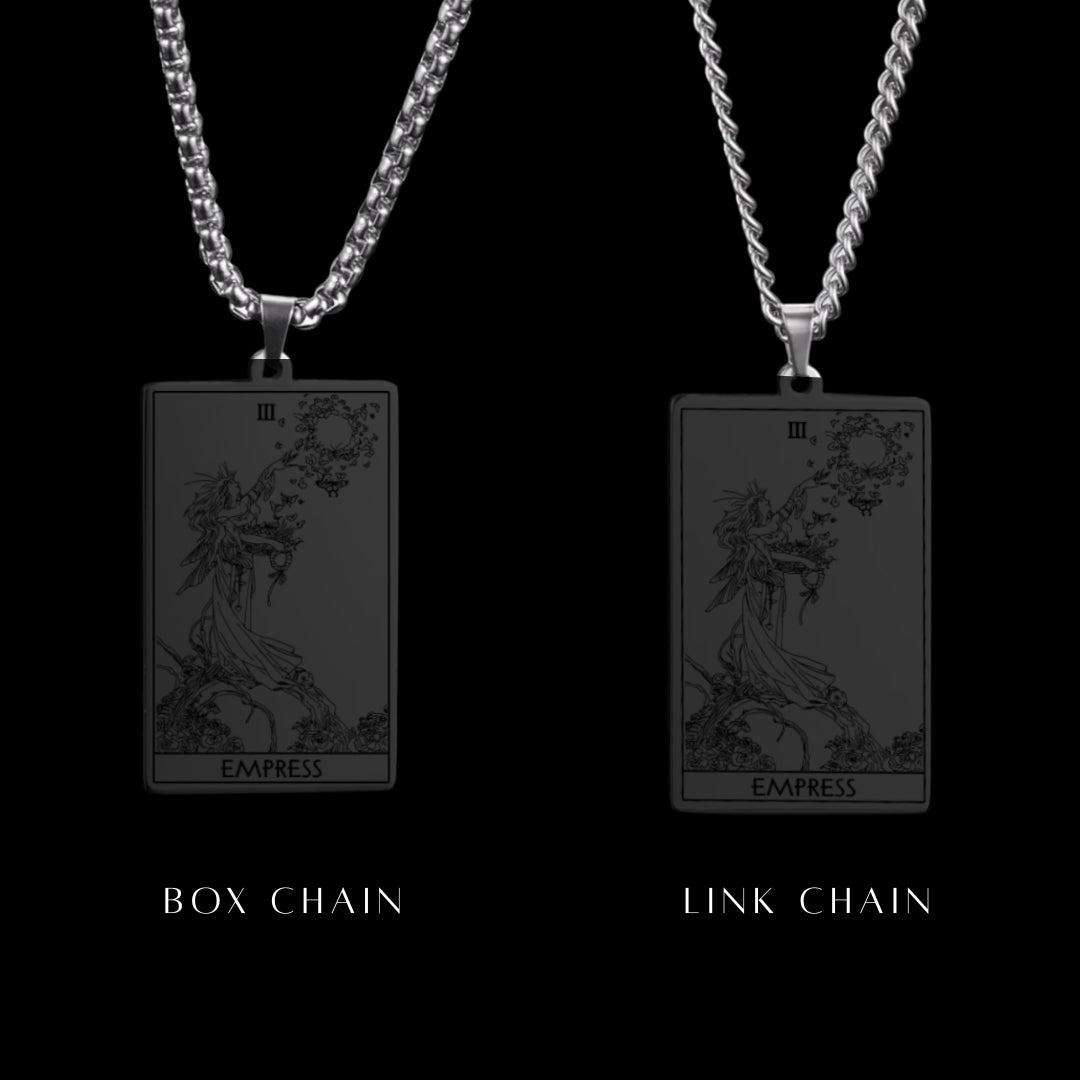Two tarot card pendants, one with a box chain and one with a link chain, on a black background.