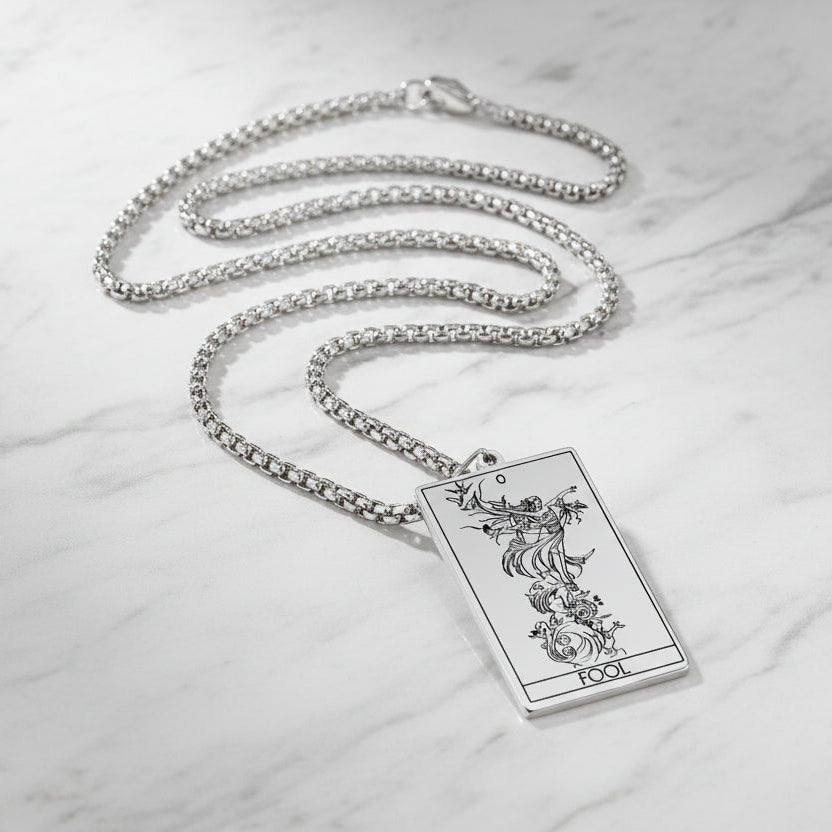 Silver necklace with a tarot card pendant on a marble surface